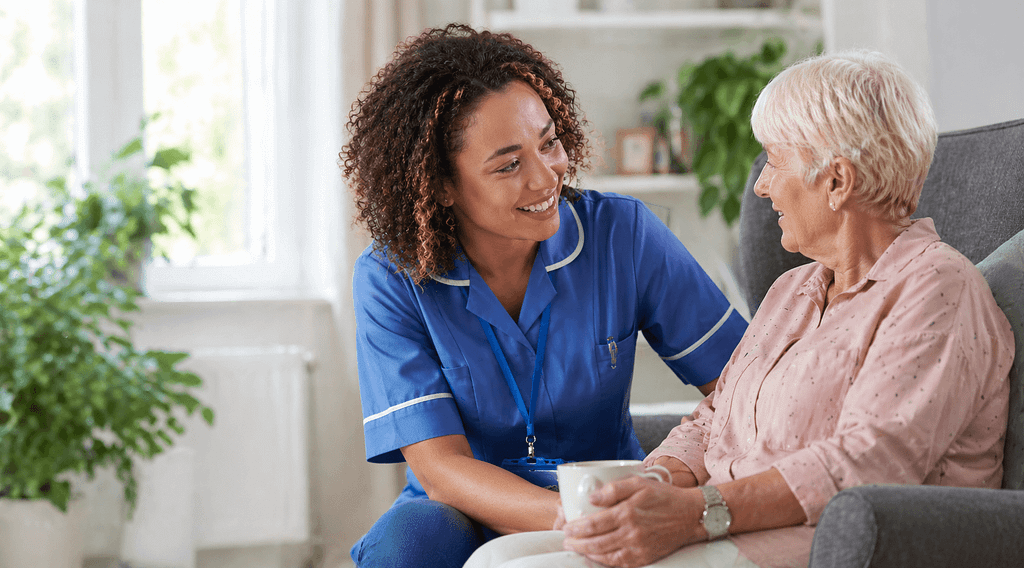 Care worker chatting warmly with an elderly woman in a home setting