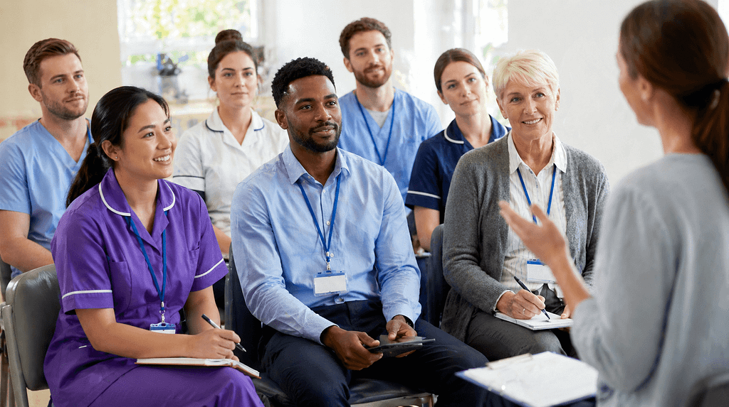 Healthcare professionals attending a training session and listening to a presenter